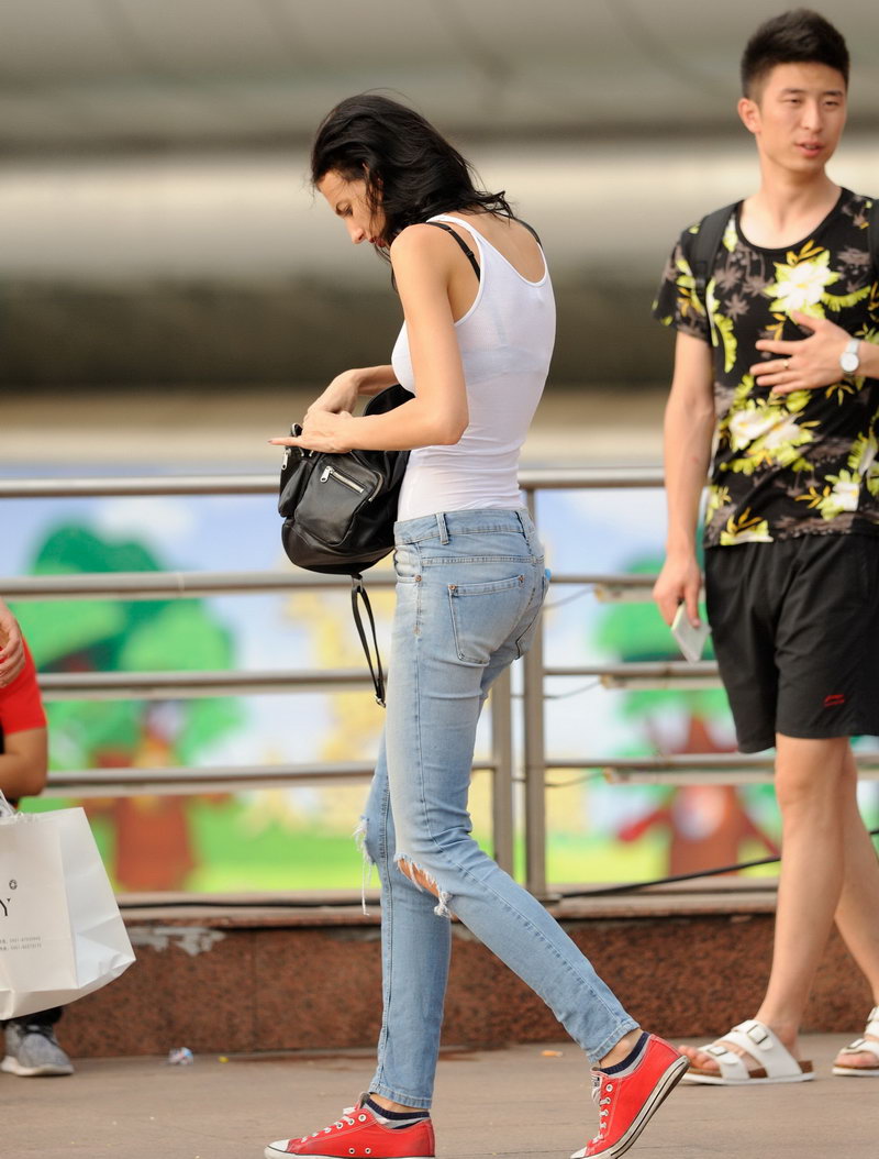 一个身穿紧身白T恤，下身搭浅色牛仔裤的骨感异国美女