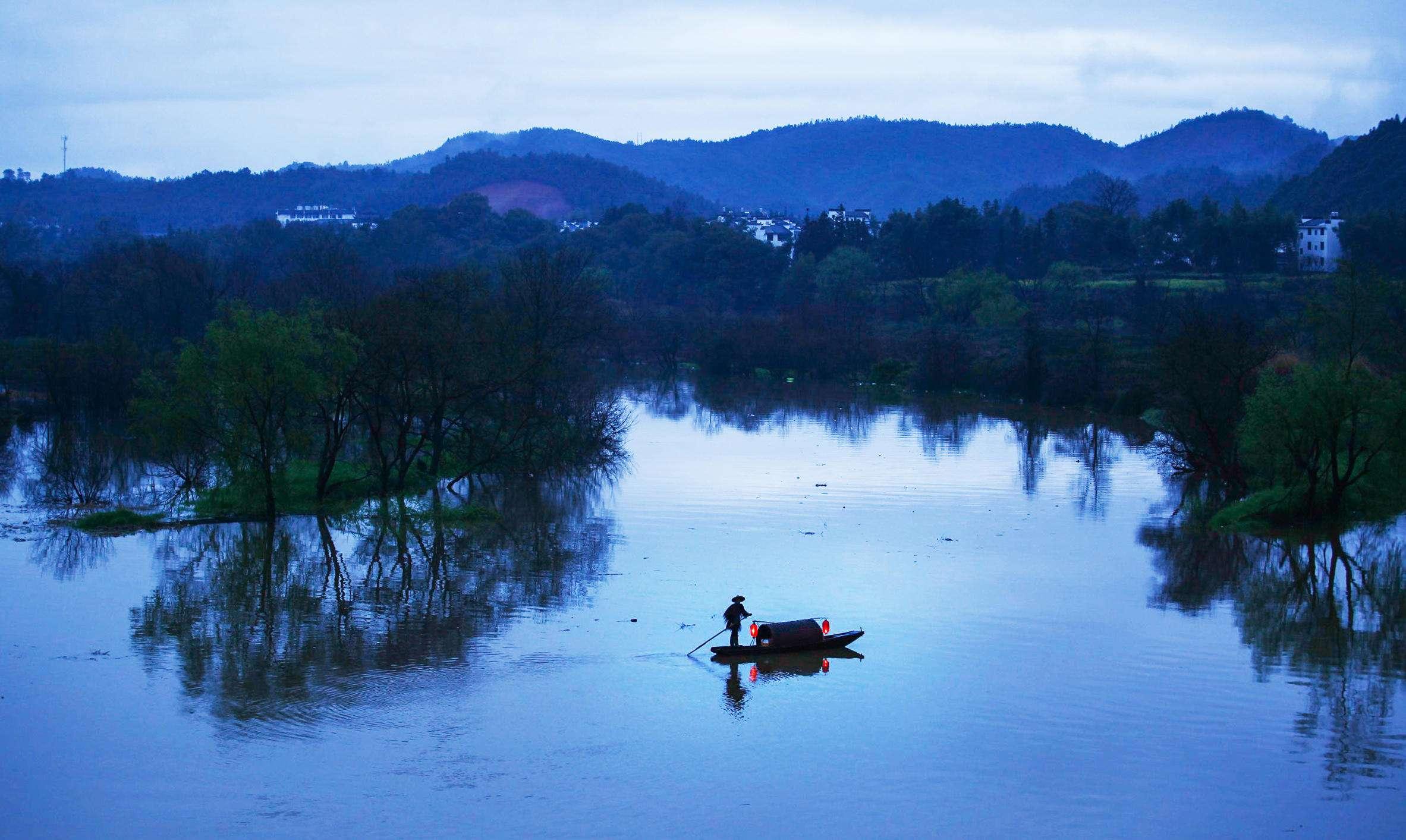 阳光照耀在江边开放的花朵之上,更增添了几分鲜艳;而在阳光的反衬之下