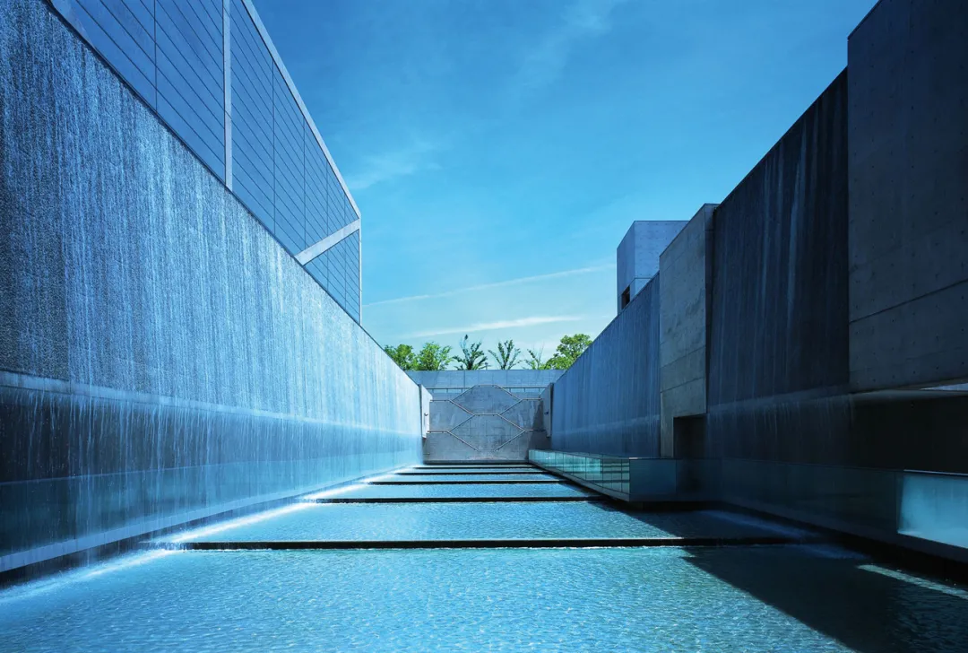必须沿着交错的步道走到下沉式的水池空间,两侧的水幕将建筑和水融合