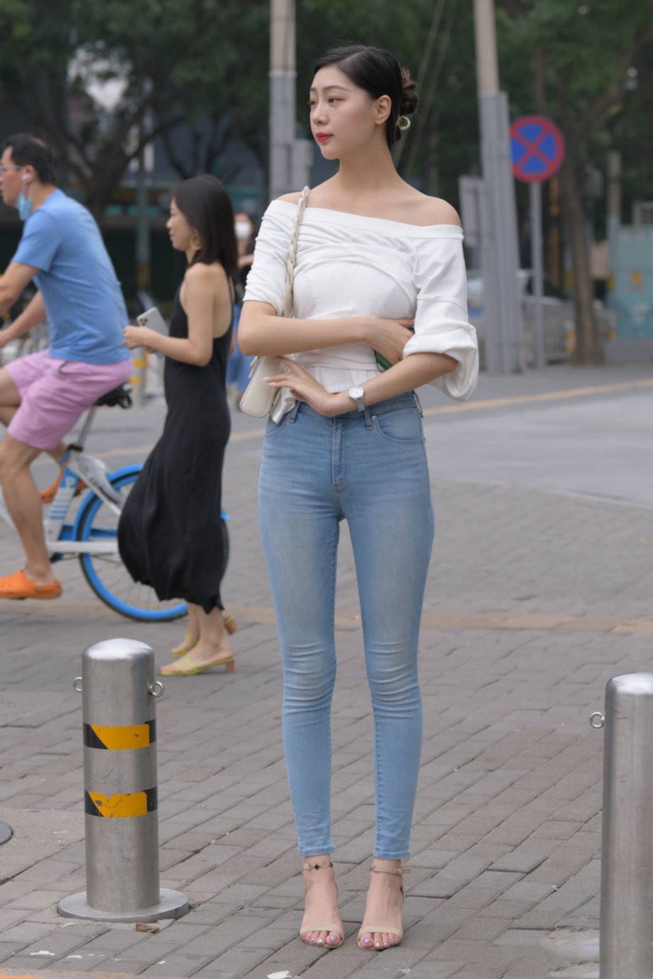 街拍美丽女子紧身牛仔瘦腿裤配白色一字肩小衫，成熟气质尽显