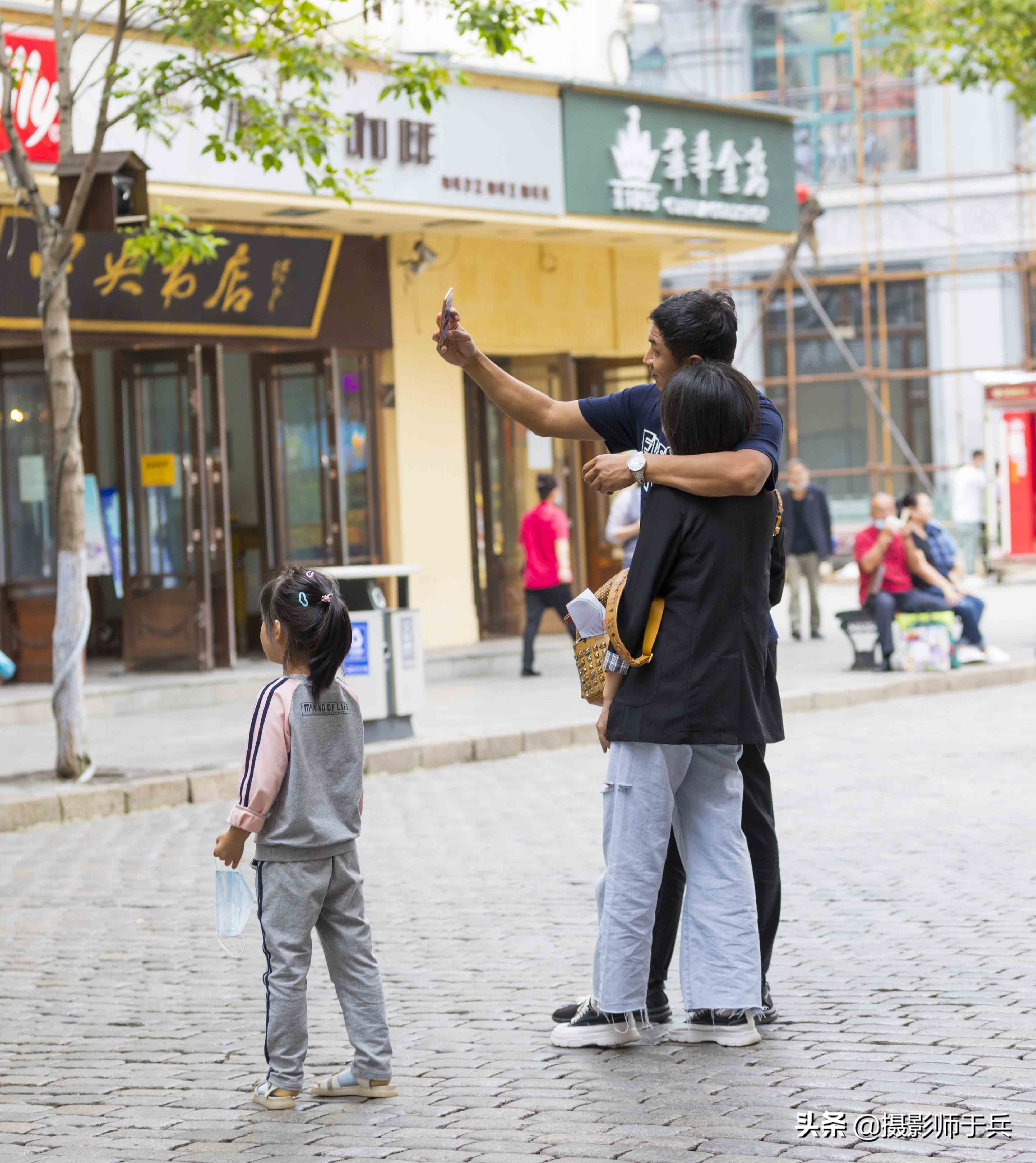 街拍；哈尔滨中央大街年轻夫妻大秀恩爱自拍，女儿变成了打酱油的