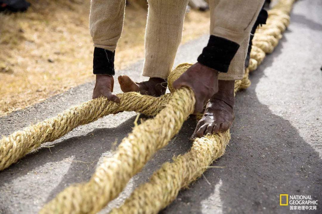 一名男子将草绳拧成粗缆线,用于铺设新桥的桥面.