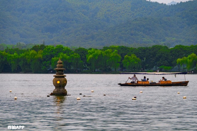 3:小瀛洲岛商店旁青山似披着一层轻纱,山顶上的塔尖,好像轻触着即将