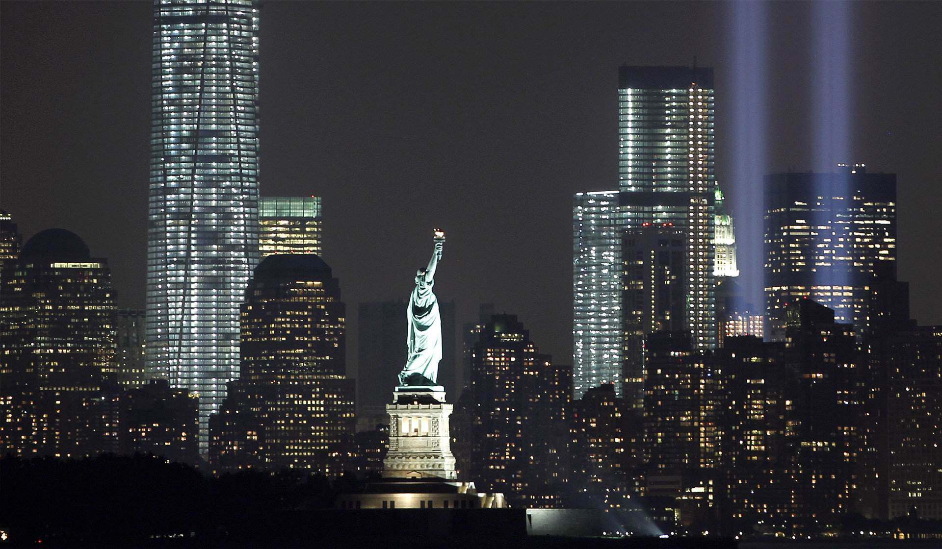自由女神左侧为新世贸中心大厦,右侧两道光束为原世贸中心大厦遗址