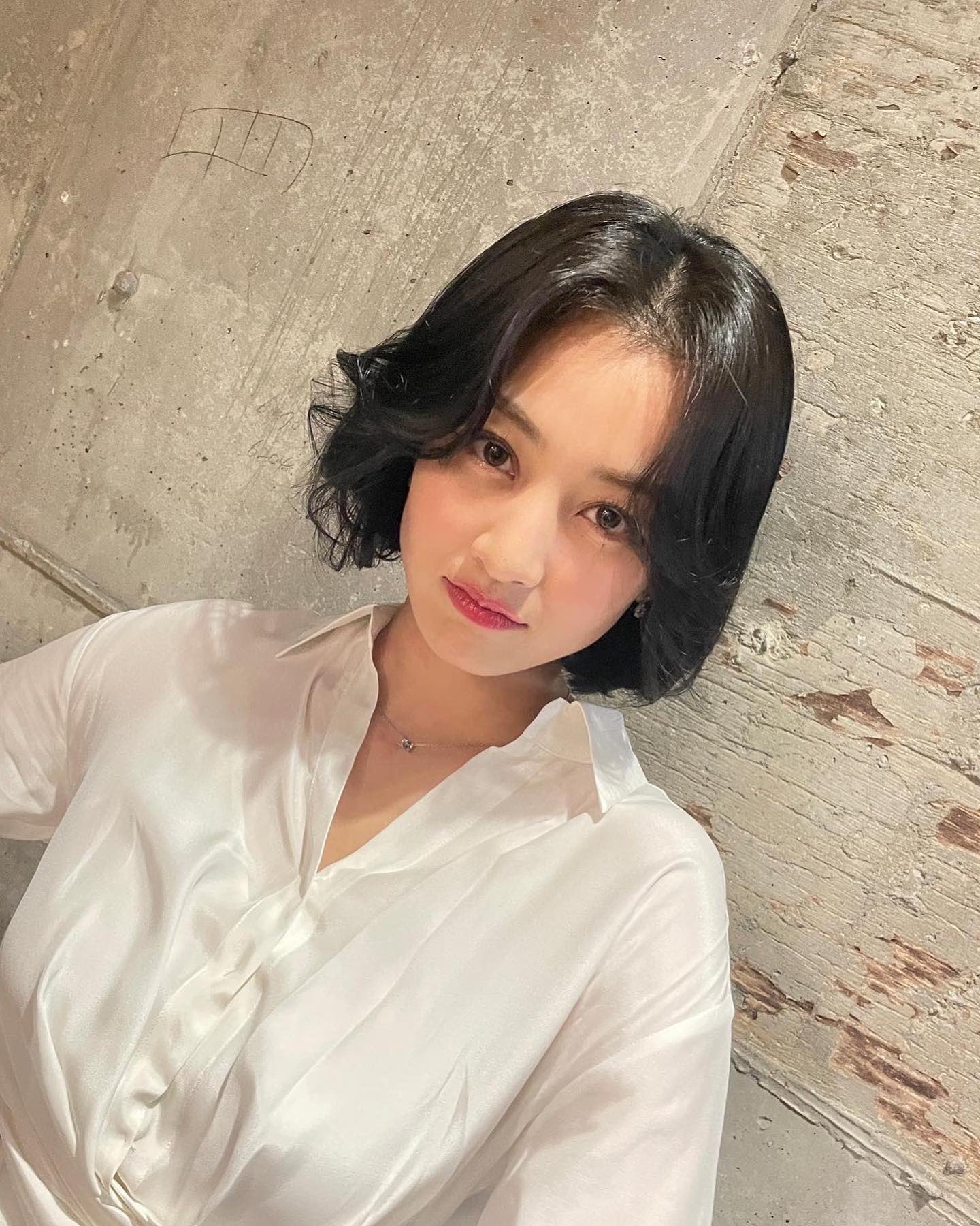 墙壁前,面对镜头摆出各种拍照的姿态,精致靓丽的容颜,志效的短发造型