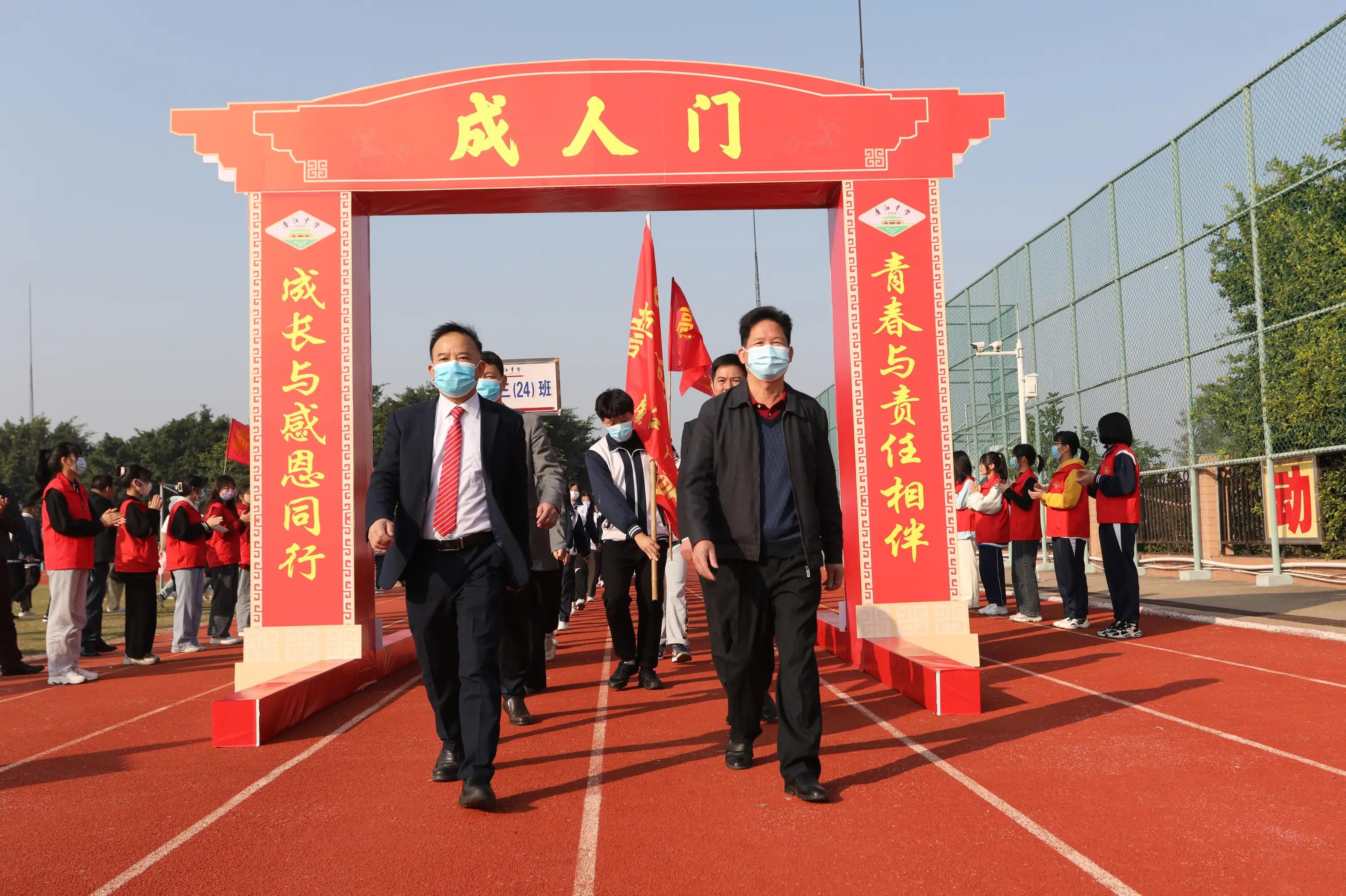 学校领导,年级主任引领各班师生手拉横幅跨越成人门,踏上成功门