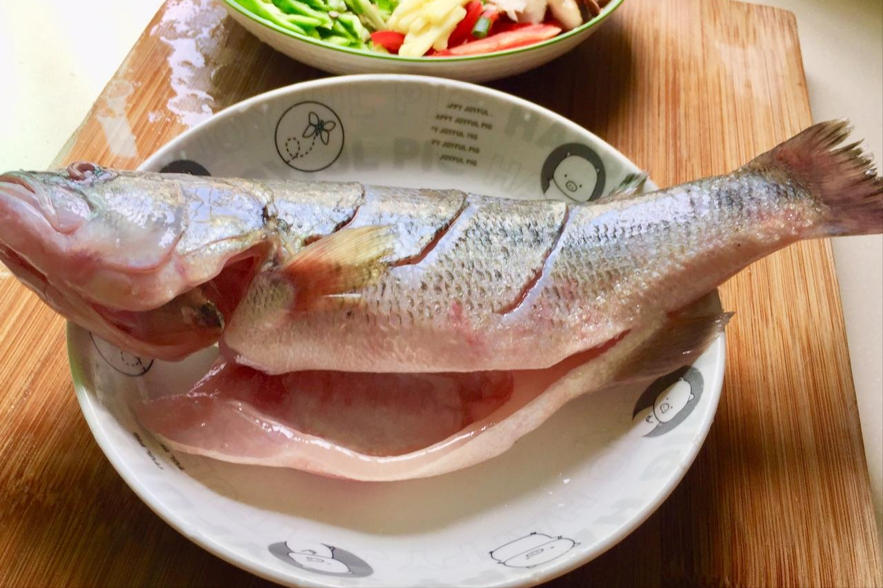 大葱一根斜切成菱形段,准备好的鲈鱼蒸好后把里面的汤汁倒出来.