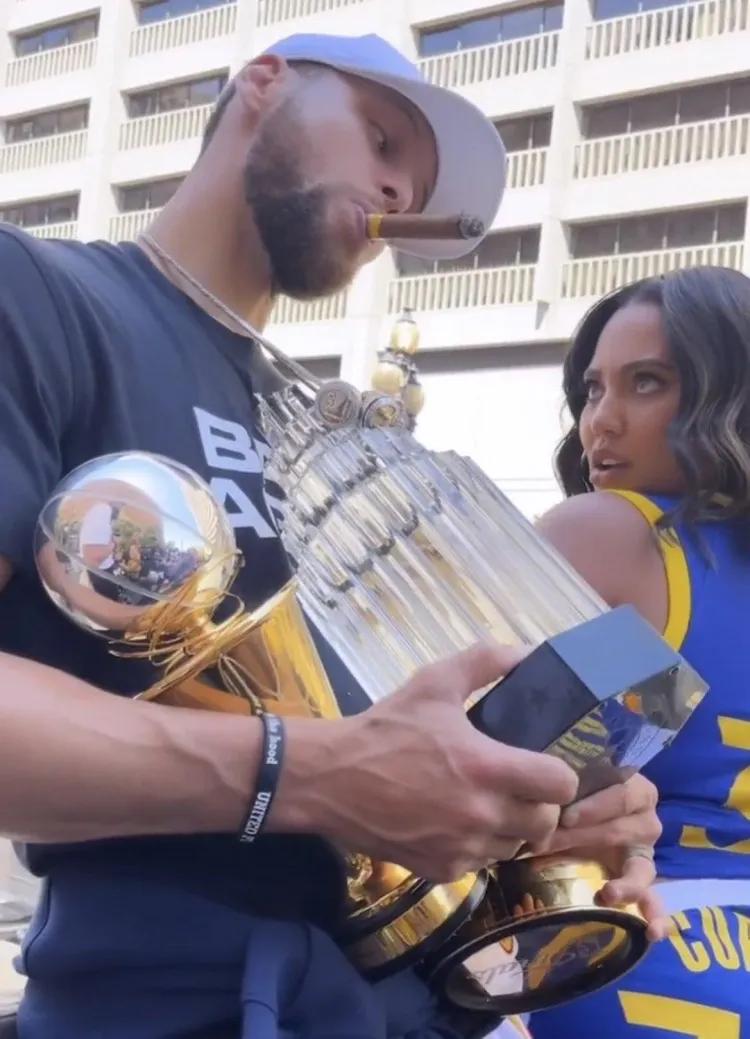 在冠军彩车上库里抱着自己的儿女拍照,向现场的观众致意,拿着奖杯表情