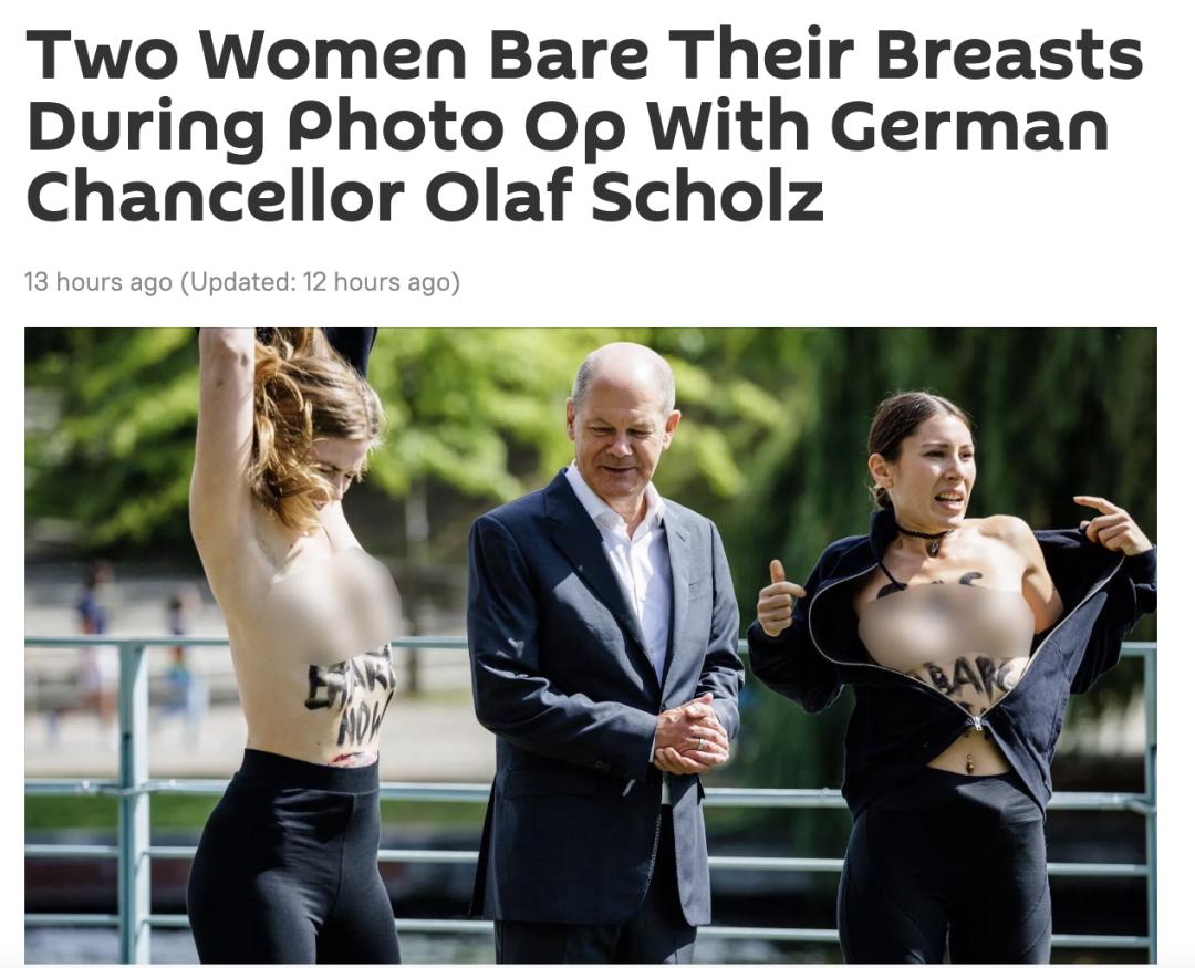 女子与德国总理合影时突然赤裸上身，胸前还写着一行字