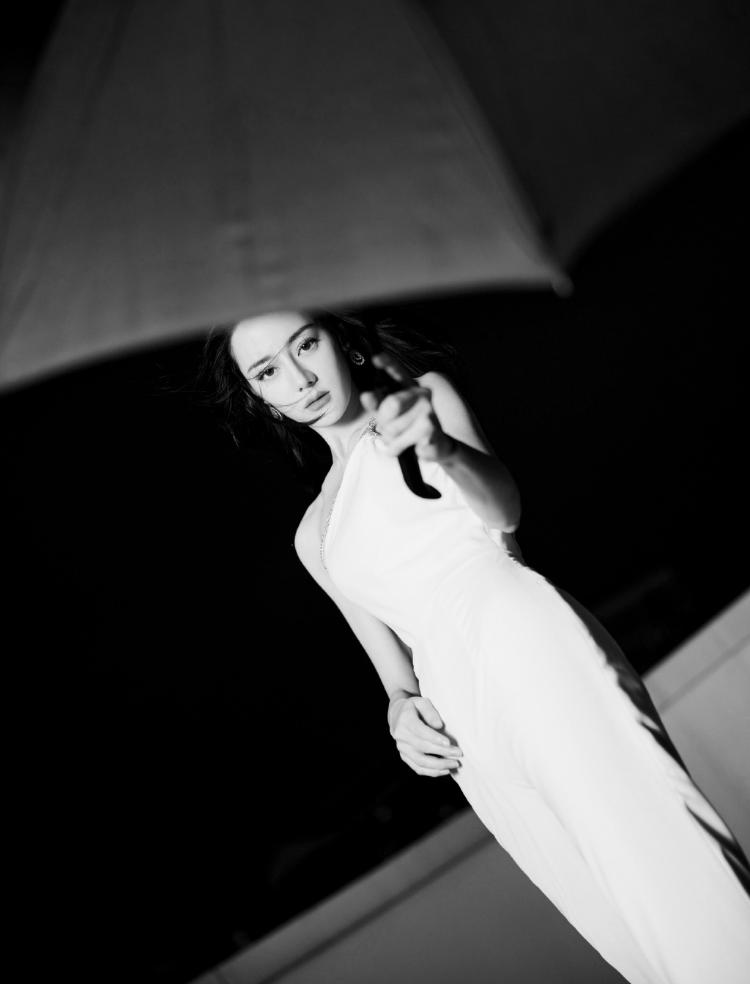 热巴穿斜肩连体裤撑黑伞 眼神霸气酷飒十足