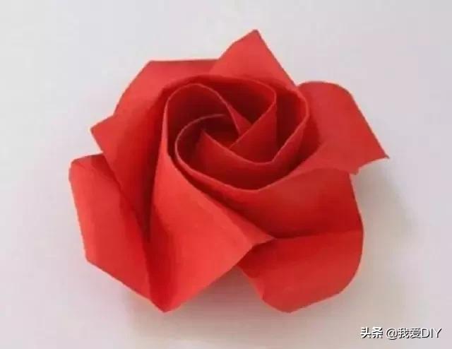 手工玫瑰花的做法:取正方形彩纸一张,角对角折叠折出痕迹后展开