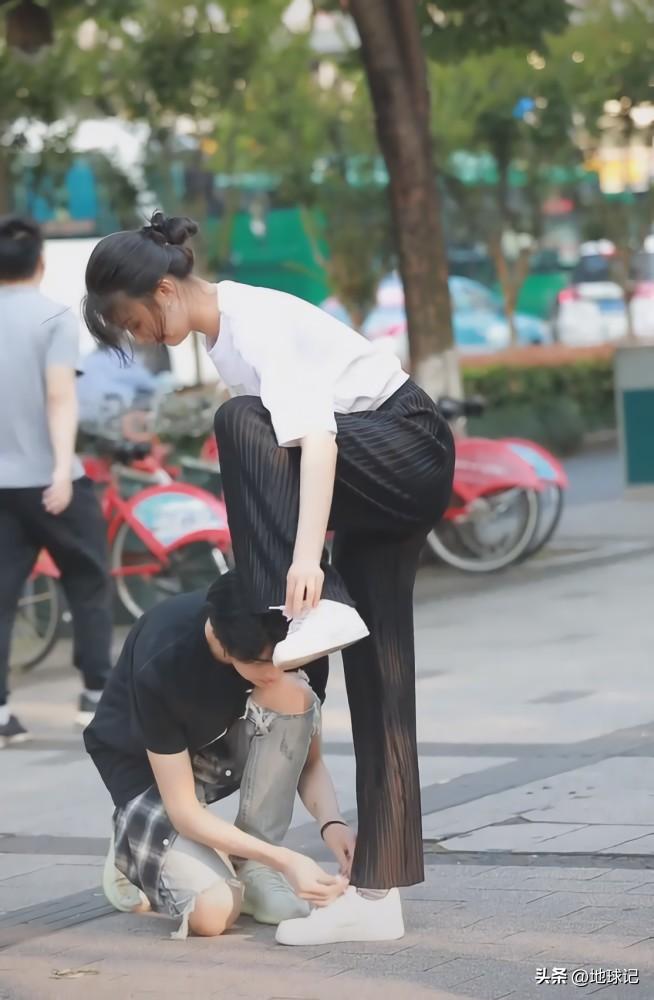 男生大街上主动帮女朋友系鞋带.